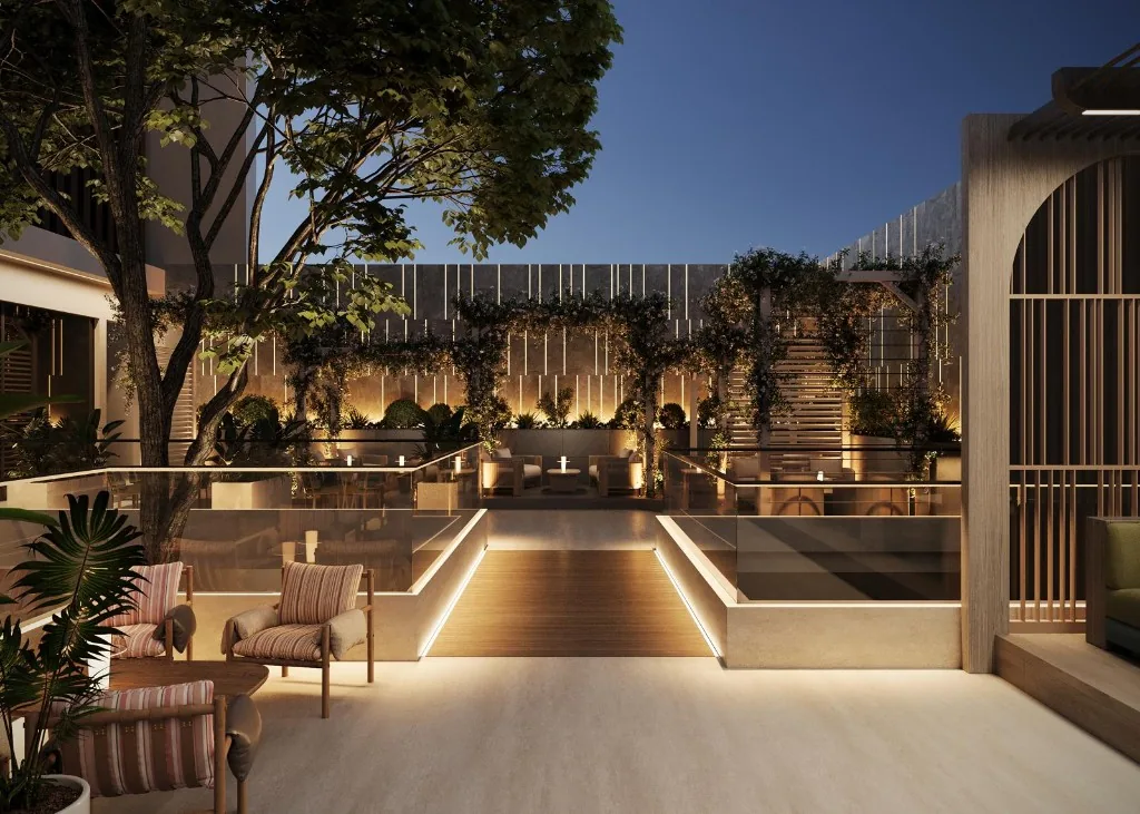 Drevené lounge kreslá Oasis Garden okolo nízkych stolíkov za súmraku