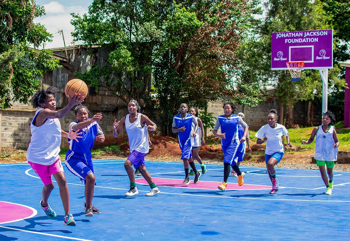 Young women playing basketball on a community court supported by Bakee Mtaani
